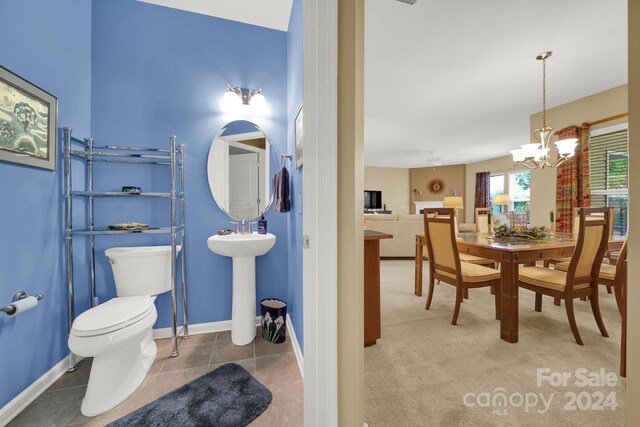 bathroom with tile patterned flooring, toilet, sink, and a chandelier