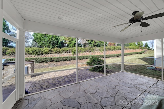 unfurnished sunroom featuring a wealth of natural light, ceiling fan, and wooden ceiling