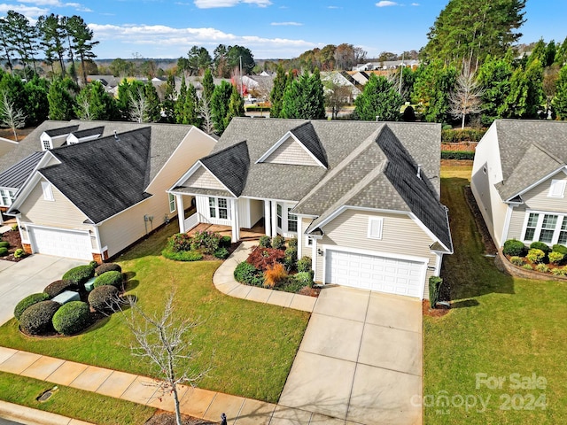 view of front of home featuring covered porch, a garage, and a front lawn