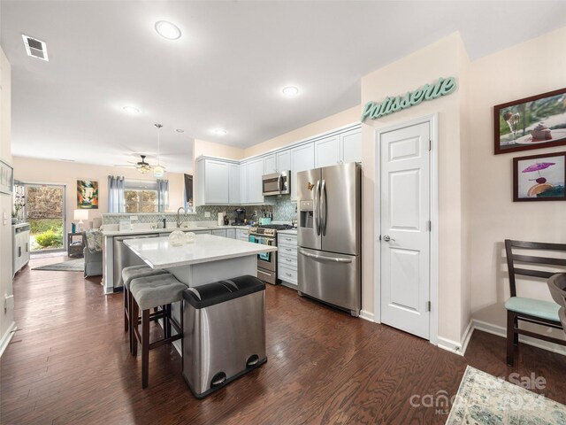 kitchen featuring a breakfast bar area, kitchen peninsula, dark hardwood / wood-style floors, and appliances with stainless steel finishes