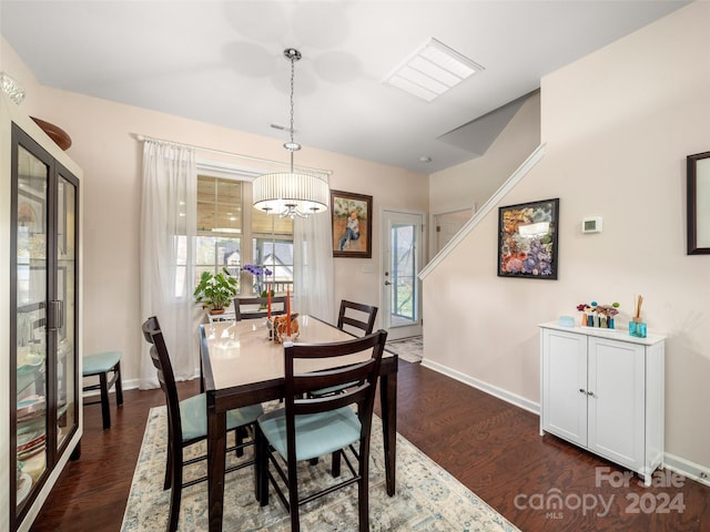 dining space featuring dark wood-type flooring and a notable chandelier