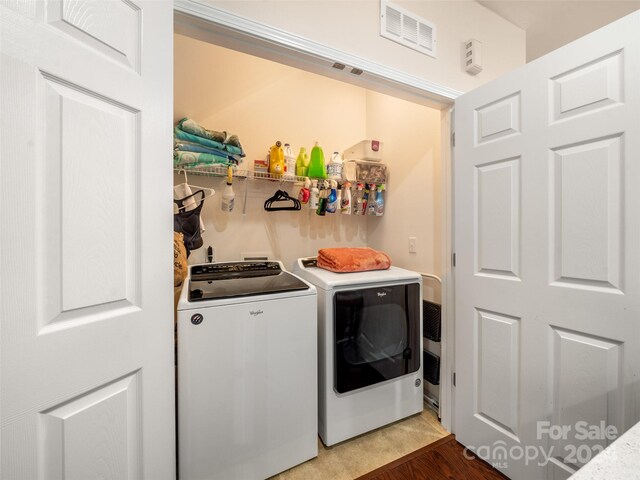 clothes washing area with hardwood / wood-style floors and washing machine and dryer