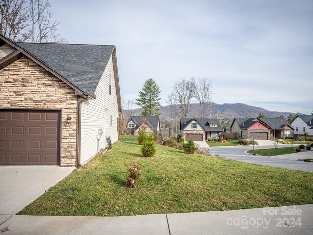 view of property exterior featuring a mountain view, a yard, and a garage