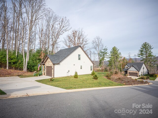 view of side of property featuring a garage and a lawn