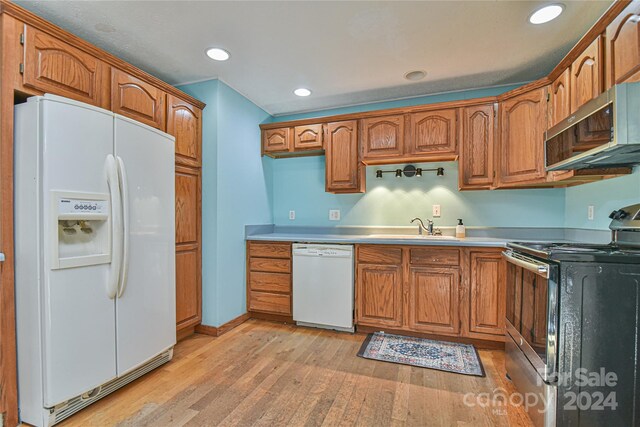 kitchen featuring light wood-type flooring, white appliances, and sink