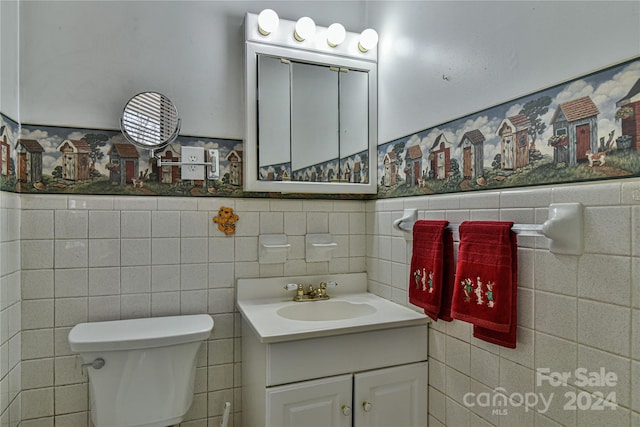 bathroom with vanity, toilet, and tile walls