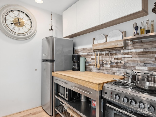 kitchen featuring light hardwood / wood-style flooring, white cabinets, stainless steel appliances, and wood counters