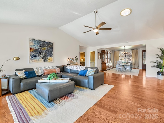 living room with ceiling fan with notable chandelier, wood-type flooring, and lofted ceiling