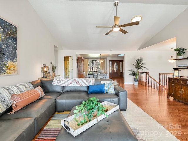 living room with ceiling fan with notable chandelier, wood-type flooring, and lofted ceiling