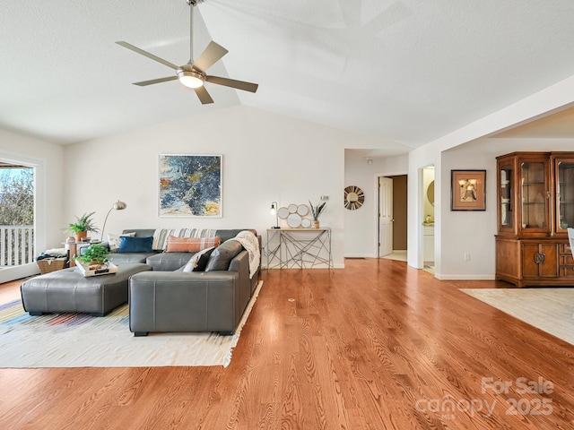 living room with hardwood / wood-style flooring, ceiling fan, and lofted ceiling