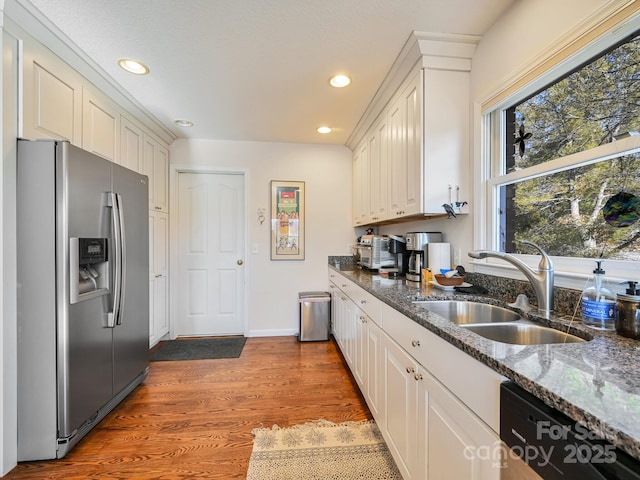 kitchen with dark stone countertops, stainless steel fridge with ice dispenser, sink, and white cabinets