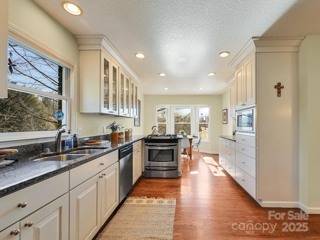 kitchen featuring white cabinets, sink, dark stone countertops, a textured ceiling, and appliances with stainless steel finishes