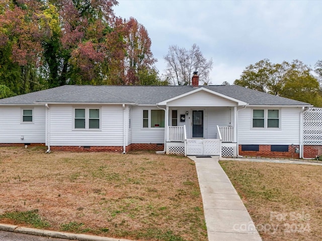 ranch-style home featuring a front lawn and covered porch