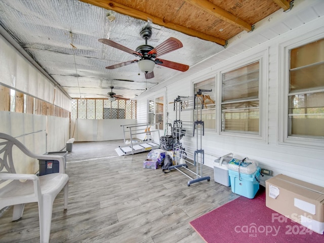 exercise area with wood-type flooring, ceiling fan, and wooden walls