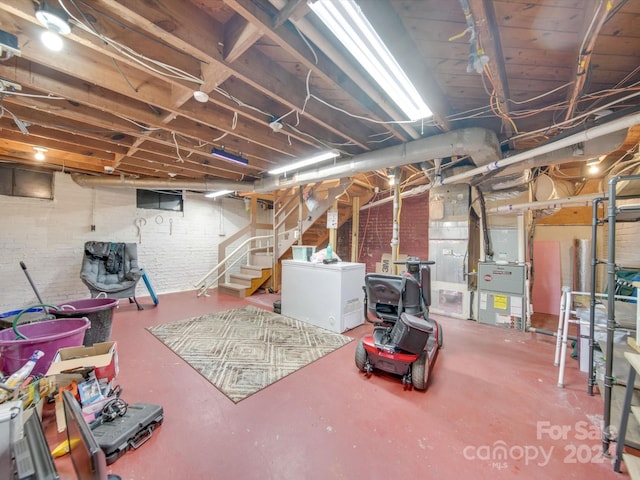 basement featuring washer / clothes dryer, brick wall, and heating unit