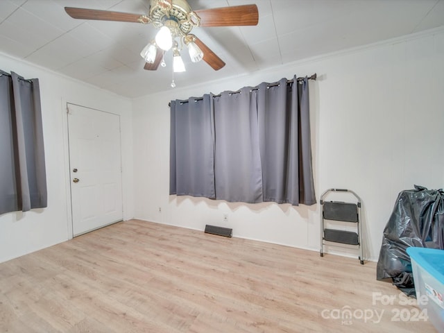 empty room featuring heating unit, ceiling fan, ornamental molding, and light wood-type flooring