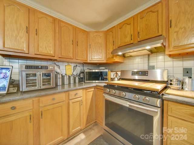 kitchen with backsplash, crown molding, and appliances with stainless steel finishes