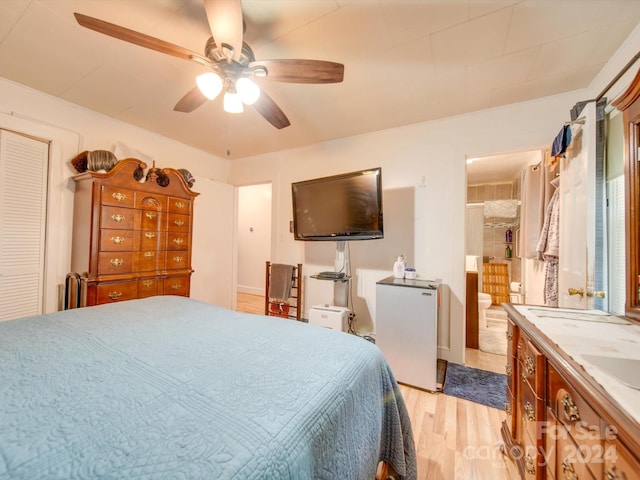 bedroom with ceiling fan, light hardwood / wood-style flooring, refrigerator, and ensuite bathroom