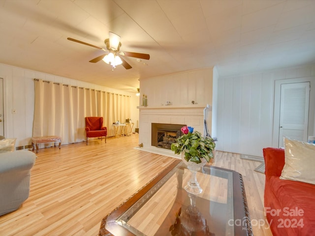 living room with hardwood / wood-style floors, ceiling fan, and a tile fireplace