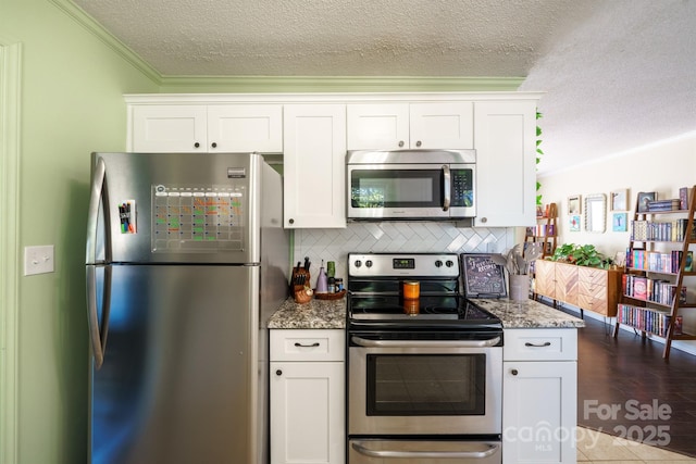 kitchen with white cabinetry, crown molding, appliances with stainless steel finishes, stone counters, and decorative backsplash