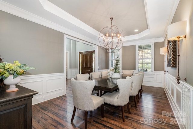 dining space with a raised ceiling, dark hardwood / wood-style flooring, ornamental molding, and a notable chandelier