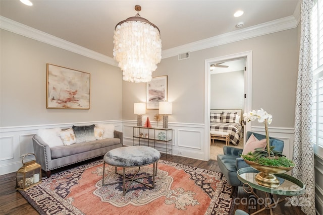 living room with wood-type flooring, ceiling fan with notable chandelier, and crown molding