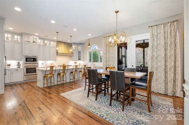 dining space with hardwood / wood-style floors and an inviting chandelier