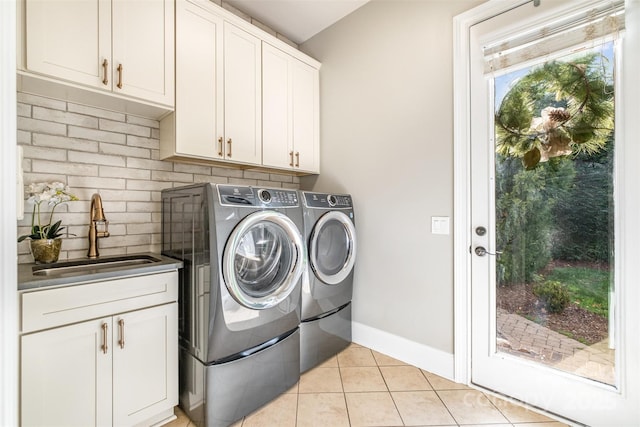 clothes washing area featuring cabinets, light tile patterned floors, washing machine and clothes dryer, and sink