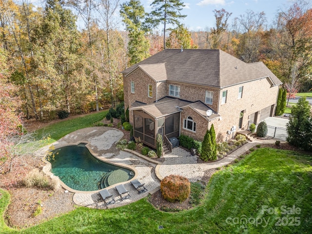 rear view of house featuring a sunroom and a lawn