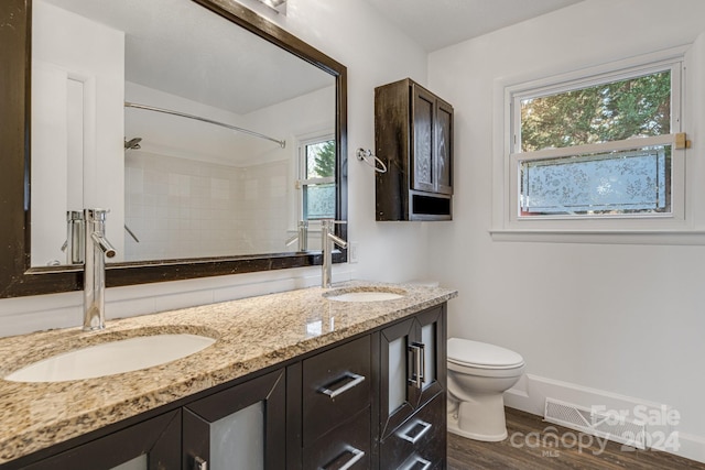 bathroom with plenty of natural light, a tile shower, wood-type flooring, and vanity