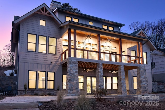 back house at dusk featuring ceiling fan and a balcony