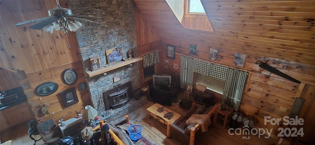 living room with hardwood / wood-style flooring, ceiling fan, and wooden walls