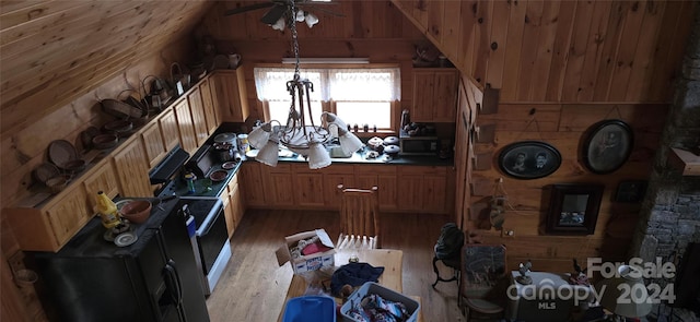 kitchen featuring ceiling fan with notable chandelier, decorative light fixtures, light hardwood / wood-style flooring, lofted ceiling, and wood walls