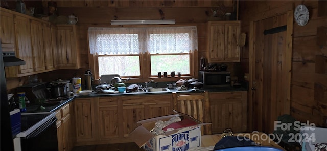 kitchen with wooden walls, black stove, extractor fan, and sink