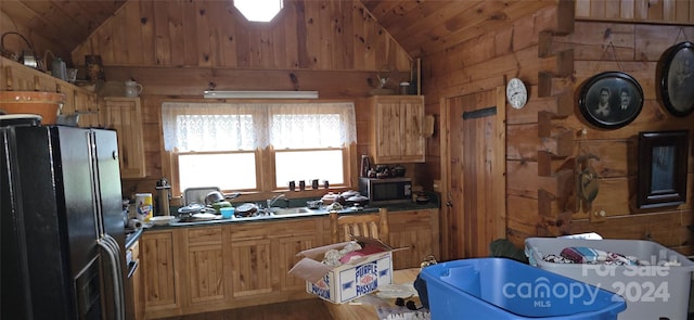 kitchen with hardwood / wood-style floors, wood walls, black fridge, and lofted ceiling