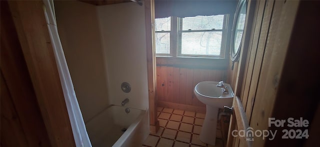 bathroom with tile patterned floors, wood walls, and  shower combination