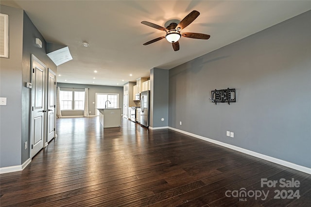 unfurnished living room with ceiling fan, dark hardwood / wood-style flooring, and sink