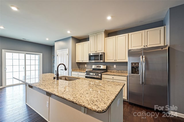 kitchen with appliances with stainless steel finishes, dark hardwood / wood-style flooring, light stone counters, and sink