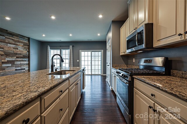 kitchen with light stone countertops, sink, dark wood-type flooring, cream cabinetry, and appliances with stainless steel finishes