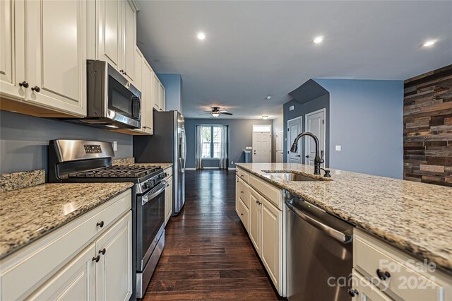 kitchen featuring sink, light stone countertops, appliances with stainless steel finishes, dark hardwood / wood-style flooring, and white cabinetry