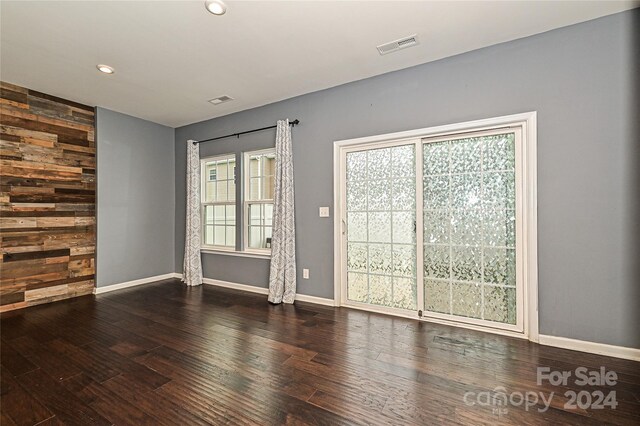 unfurnished room featuring wooden walls and dark wood-type flooring