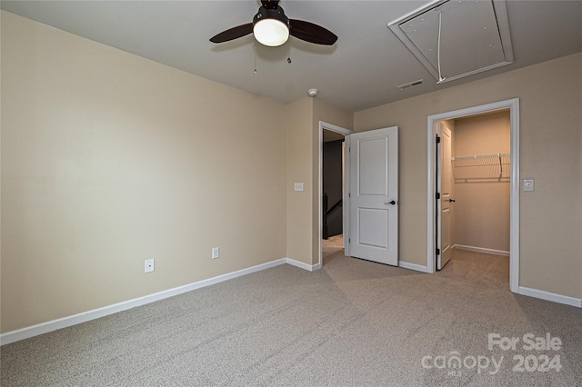 unfurnished bedroom featuring a spacious closet, a closet, ceiling fan, and light carpet