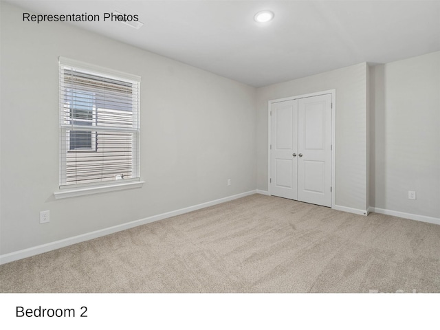 unfurnished bedroom with light colored carpet and a closet