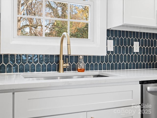 room details with white cabinets, decorative backsplash, dishwasher, and sink