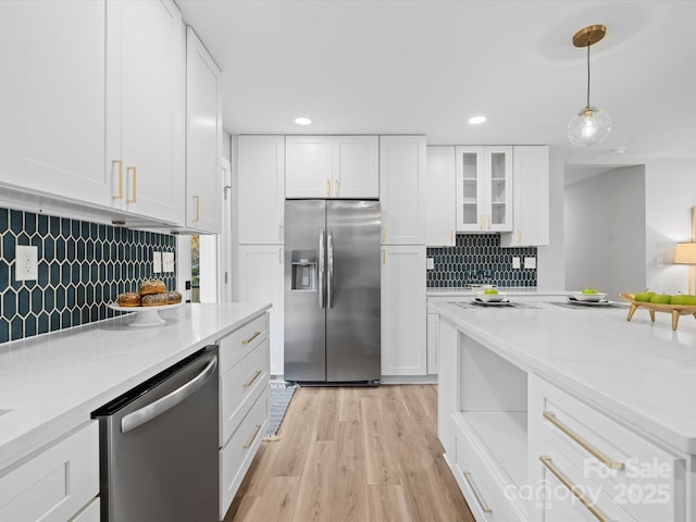 kitchen featuring white cabinets, appliances with stainless steel finishes, decorative backsplash, and hanging light fixtures