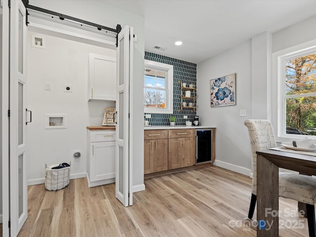 bar featuring wine cooler, white cabinets, and light wood-type flooring