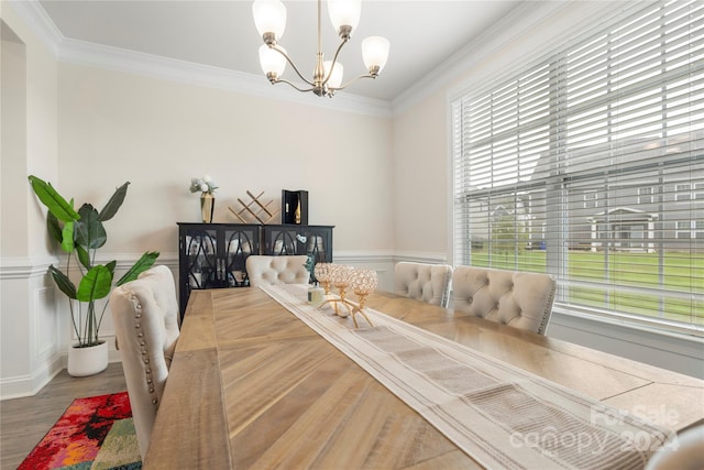 dining area with hardwood / wood-style flooring, an inviting chandelier, a wealth of natural light, and ornamental molding