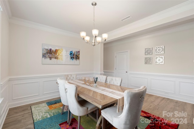 dining space featuring an inviting chandelier, ornamental molding, and hardwood / wood-style flooring