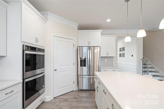 kitchen featuring white cabinets, light hardwood / wood-style floors, ornamental molding, and stainless steel appliances