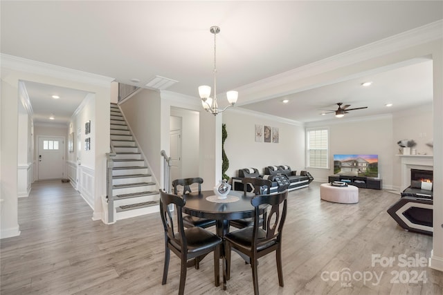 dining room with ceiling fan with notable chandelier, light wood-type flooring, and ornamental molding